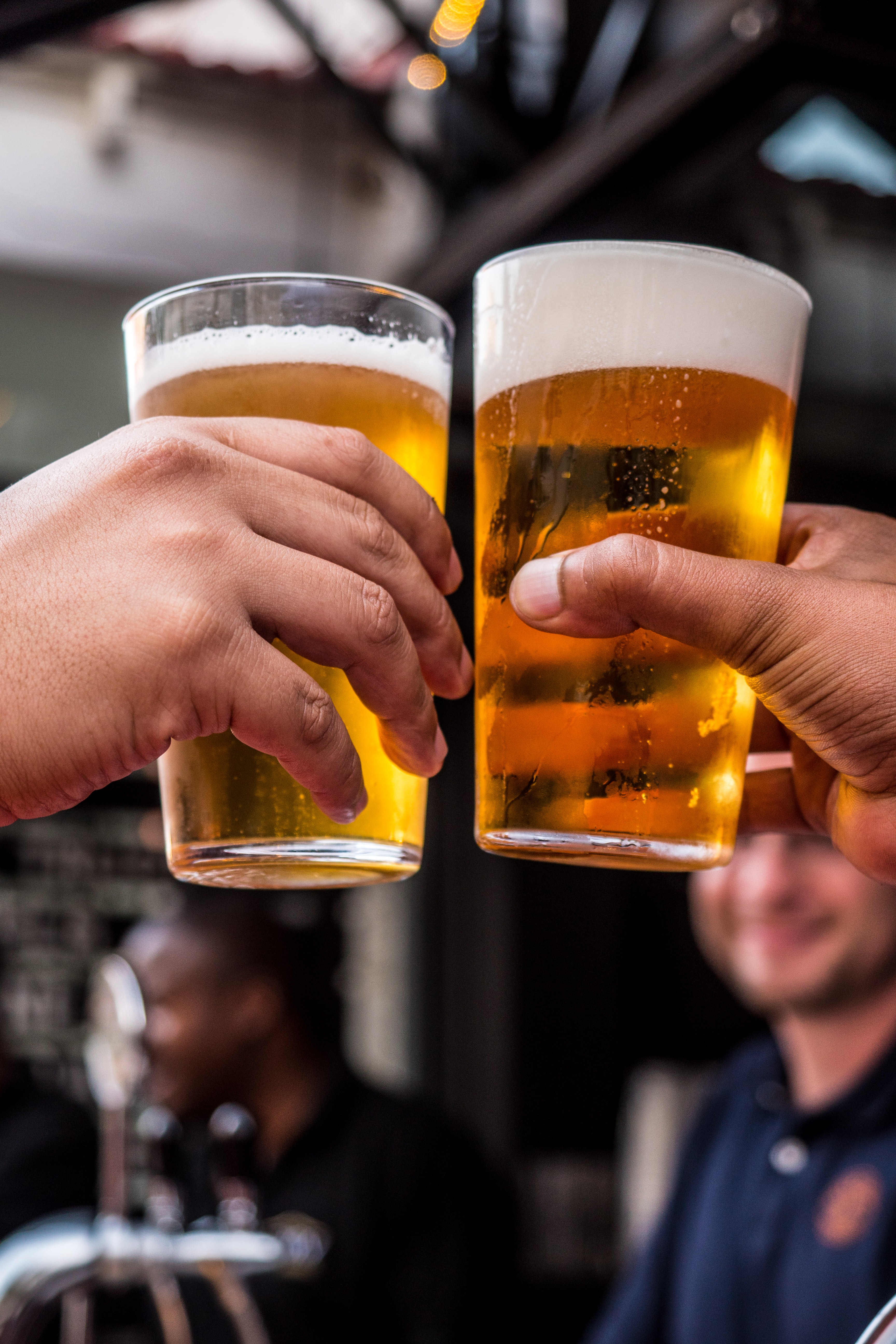 Two glasses of beer being clinked. 