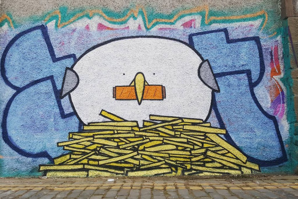 Grafitti of a seagull protecting a pile of fries