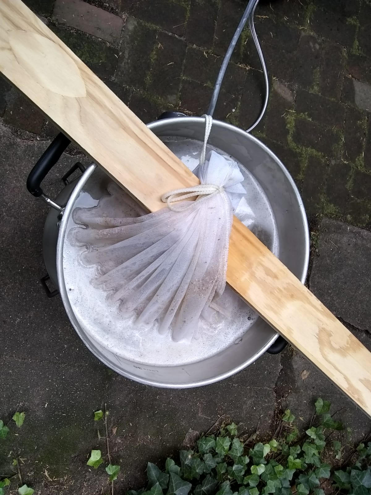 A bag of grain dunked into the pot of water.