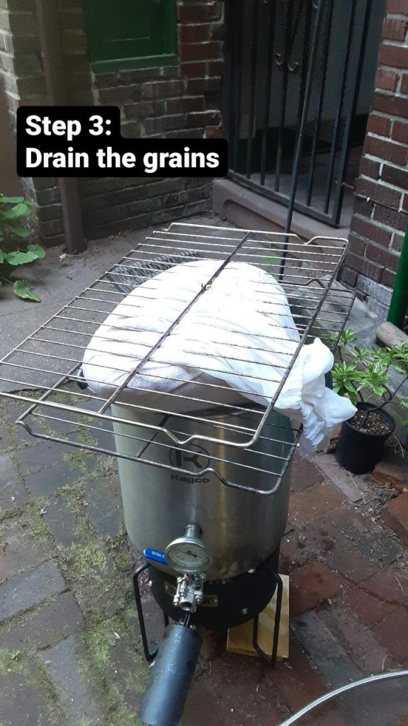 Picture of the mesh bag being drained on top of the post between two oven shelves. Text: Step 3: Drains the grains.