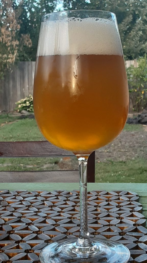 Glass of beer, hazy light brown in color, with about an inch of head.