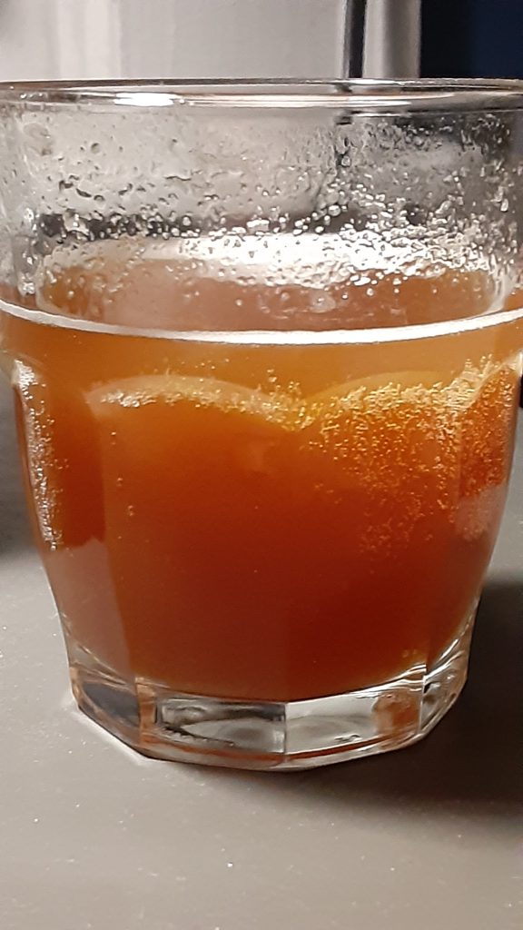 A glass of golden brown mead.
